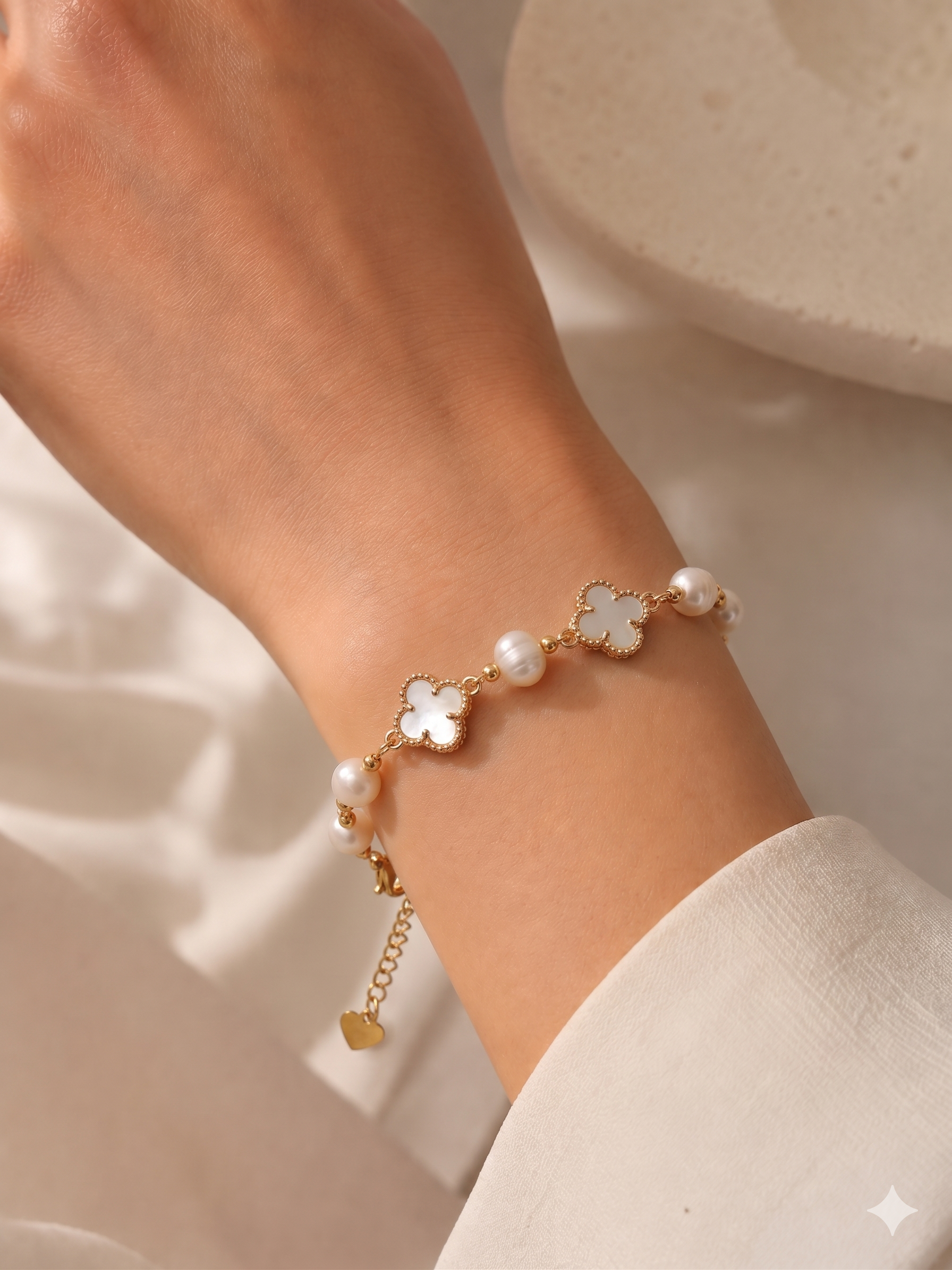 Náramek s bílými perličkami a růžovými čtyřlístky ze zlatě tónované chirurgické oceli – symbol elegance a štěstí